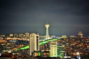 Bir şehir geceleri yeşil bir kuleyle aydınlatılıyor.